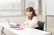オフィスやレンタルスペースでパソコンを操作する女性。オンラインで快適に仕事をするイメージ。