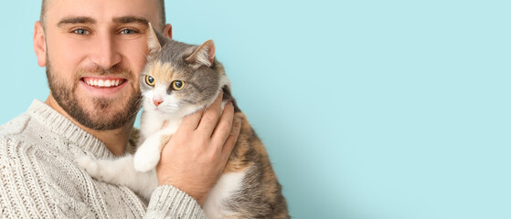 Poster - Happy young man and cute cat on light blue background with space for text