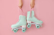 Woman holding vintage roller skates on color background