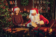 © ZaStock - Cute girl Santa Clause helper steals candy while Santa checks gift letters. Christmas scene