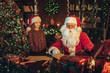 © ZaStock - Little girl watching like santa claus check gift letters with candies. Christmas scene.