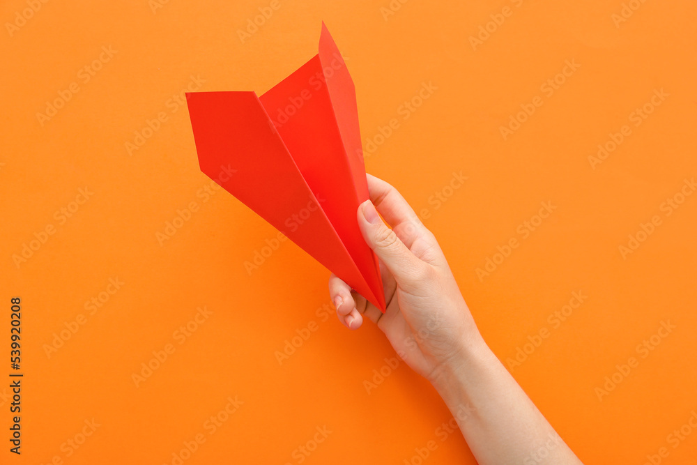 Woman with red paper plane on orange background