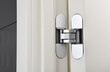 New modern metal door hinges hidden on white wooden doors.