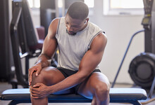 Black Man, Fitness And Knee Injury In Gym After Workout, Training Or Intense Exercise. Earphones, Health And Bodybuilder Male From Nigeria Suffering From Sore Leg, Muscle Pain Or Joint Inflammation.