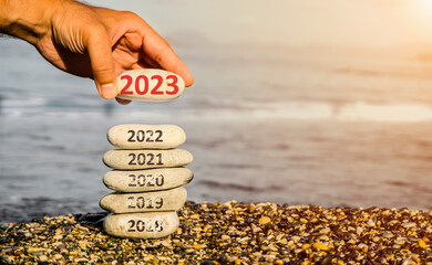 Happy new year 2023 replace old 2022. New Year 2023 is coming concept idea on beach. Creative photo image can be used as display, printed canvas, website banner, social media post.	