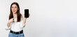 Happy beautiful woman smiling, pointing at mobile phone screen, showing advertisement, website, standing over white background