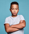 © N Felix/peopleimages.com - Problem, crossed arms and portrait of child with angry facial expression, attitude and upset over conflict on mockup studio. Anger, moody boy and unhappy African youth kid isolated on blue background