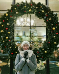 Girl on the background of a Christmas wreath on the street.