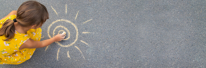 Wall Mural - The child draws the sun on the asphalt. Selective focus.