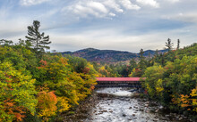 Historic Covered Bridge Crosses A River With Trees In Fall Color On The Banks And A Distant Hills, Albany Covered Bridge, White Mountain National Forest, New Hampshire