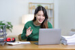 © Wasan - Beautiful Asian woman working on laptop and documents in home office.