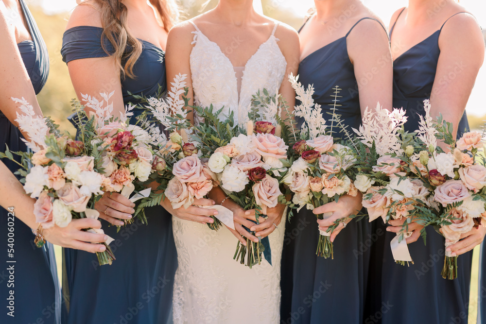 flowers with navy blue bridesmaids dresses Bride and holding bouquets. Bridesmaids are wearing dresses. Bouquet has roses and wildflowers. Stock Photo Great for any cup