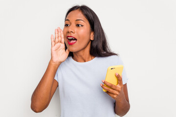 Wall Mural - Young indian woman using mobile phone isolated on white background shouting and holding palm near opened mouth.