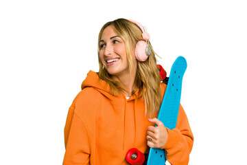 Wall Mural - Young caucasian skater woman isolated on green chroma background looks aside smiling, cheerful and pleasant.