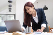 © wichayada - Asian Business woman using calculator and laptop for doing math finance on an office desk, tax, report, accounting, statistics, and analytical research concept