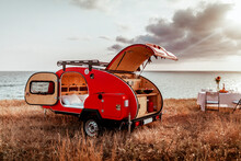 Red Camper For Traveling By Car, Against The Backdrop Of A Beautiful Landscape Sky, Sea And Sunset, Cozy Camping, Beautiful Camp, Lunch Outdoors By The Sea On The Coast Of The Beach