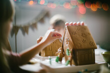 Siblings Decorate Gingerbread Houses With Candy At Christmas