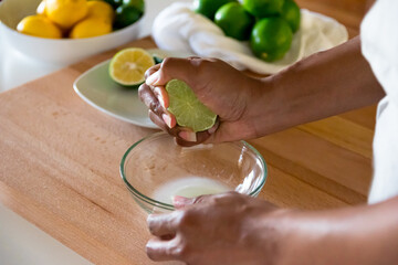 Black woman, African American woman hand squeezing fresh lime juice into glass bowl