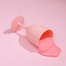 Creative Layout, Glass With Spilled Liquid On Bright Pink Background With Shadow. Visual Trend. Fresh Idea. Concept Pop