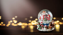 Christmas Snow Globe With Snowman On Wooden Desk With Defocused Bokeh. Stock Christmas Background