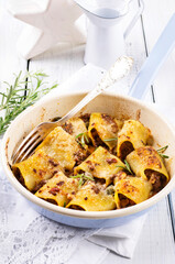 Wall Mural - Traditional Italian canneroni pasta filled with minced meat and served with parmesan as close-up in a design pan