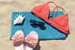 Towel, flip flops and bra on sand, top view. Beach accessories