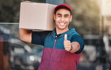Portrait, Box And Delivery Worker With Thumbs Up Gesture And A Big Smile Carrying Cargo, Stock Or A Package. Happy Delivery Man With A Thumb Up Holding A Cardboard Packaging Or Mail Post Outdoors