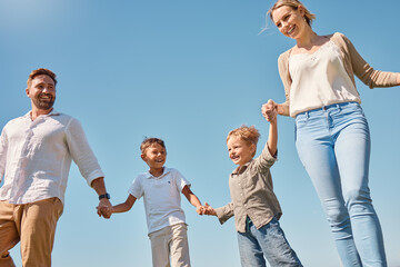 Poster - Family, children and sky with a mother, father and boy siblings walking hand in hand outdoor in summer. Freedom, love and kids with a brother holding hands with his parents while on a walk together