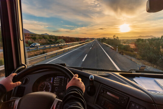 view from the driver's seat of a truck of the highway and a landscape of fields at dawn, with a dram