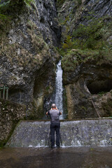 Wall Mural - Nature photographer with camera by a waterfall