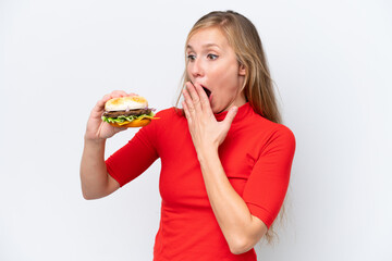 Young blonde woman holding a burger isolated on white background with surprise and shocked facial expression