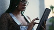 A black latina young woman holding tablet device outside. Profile of a Brazilian female person touching device screen standing outdoors
