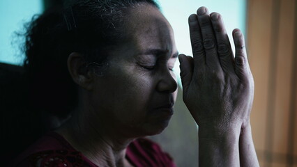 One hispanic senior woman praying to God. A religious older South American person