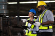 © amorn - Group of male and female engineer work with digital tablet for check or maintaining heavy metal machine at the industry factory area. Team of technician wear safety uniform working in the factory