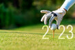 Leinwandbild Motiv Close up hand Golfer woman putting golf ball for Happy New Year 2023 on the green golf for new healthy.  copy space. Healthy and Holiday Concept