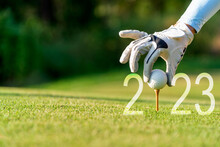 Close Up Hand Golfer Woman Putting Golf Ball For Happy New Year 2023 On The Green Golf For New Healthy.  Copy Space. Healthy And Holiday Concept