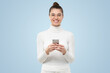 © Damir Khabirov - Studio shot of beautiful girl, looking straight at camera, smiling while holding smartphone