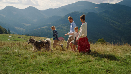 Parents kids walking dog on mountain hill. Girl with mother holding husky leash.