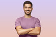 © Damir Khabirov - Smiling handsome man in t-shirt standing with crossed arms on purple background