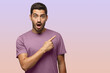 © Damir Khabirov - Young surprised man in purple t-shirt pointing right with his finger, shouting WOW
