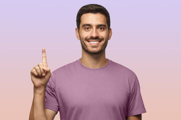 Wall Mural - Attractive young man in purple t-shirt pointing up with his finger isolated on purple