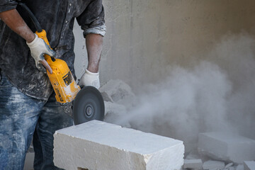 a worker cutting stone for wall construction