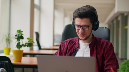 Developer, video editor man in headphones working with laptop at spacious coworking alone enjoying music. Stylish creative musician producer listens song in office alone. Online gamer playing games.