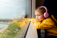 A Girl In Headphones On A Train Looks Out The Window. Journey.