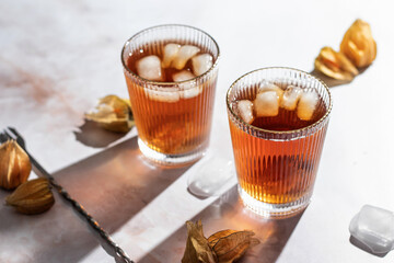 Orange healthy cold beverage cocktails decorated with physalis berry on marble background. Drink Photo with hard light and clear shadows. Autumn party concept