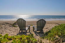 Adirondack Beach Chairs In The Sand With A View Of The Sparking Ocean