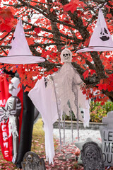 Wall Mural - White witch hats and ghost skeleton hanging on the tree with red leaves. Halloween concept