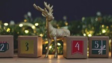 Beautiful Advent Calendar Three Kraft Boxes With Numbers 2,3,4,5 With Deer Christmas Decor And A Burning Garland On A Wooden Table, Close-up Side View In Slow Motion And Zoom Out.