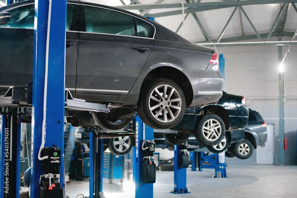 cars raised on car lifts located in the workshop of a car service の ...