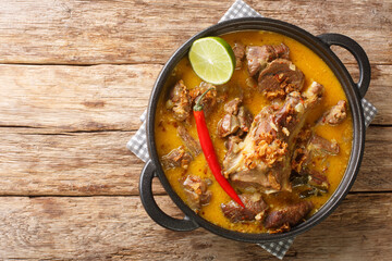 Poster - Indonesian food gulai kambing goat curry spicy stew closeup on the pan on the wooden table. Horizontal top view from above